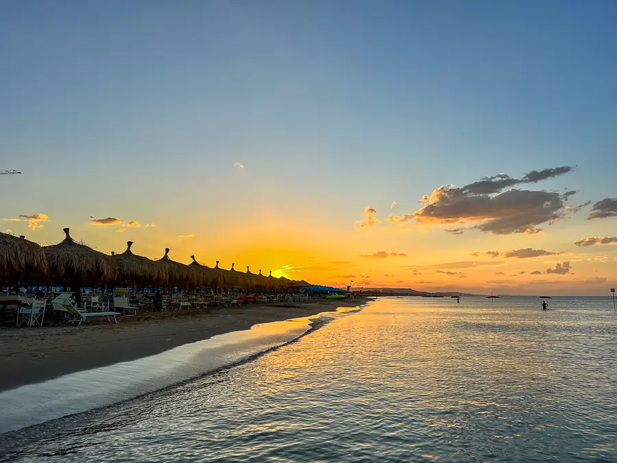 Alba dorata sull'Adriatico con gli ombrelloni di paglia sulla spiaggia