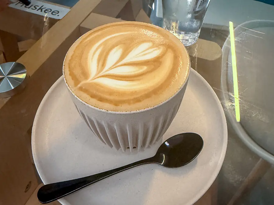 Un cappuccino con la schiuma disegnata a foglia su un tavolino