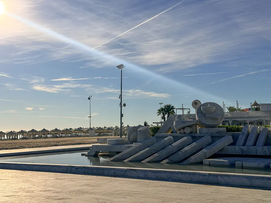 La fontana La Nave di Pietro Cascella sul lungomare, con il cielo striato di nuvole