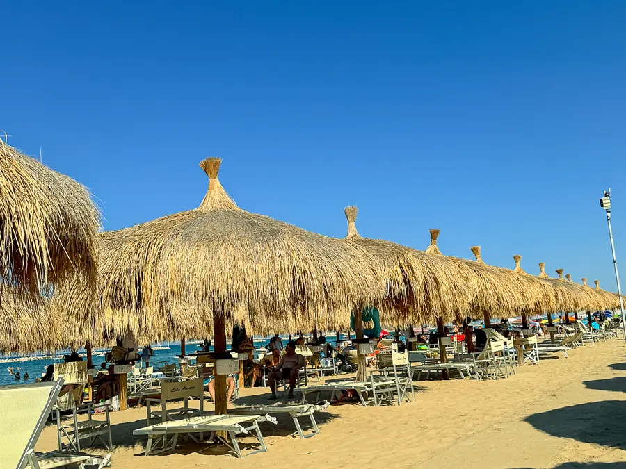 Ombrelloni di paglia e lettini su una spiaggia di Pescara sotto un cielo azzurro